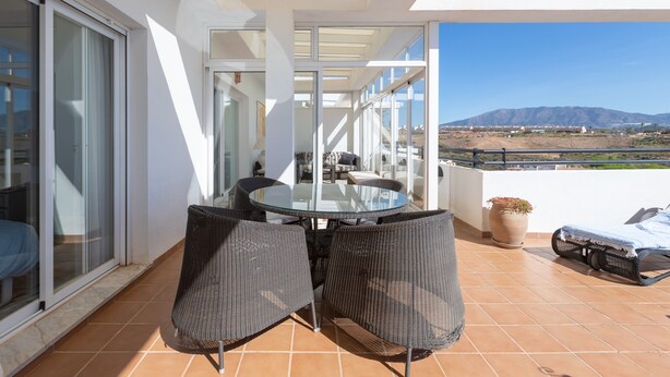 A balcony with a glass table and chairs, a potted plant, and a view of a distant landscape. - Penthouse with a fantastic view, Mountain View, Sea View, Terrace & Garden (La Cala de Mijas)