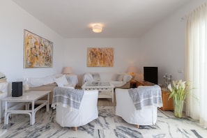 A modern living room with a sofa, armchairs, a coffee table, and two lamps. There are abstract paintings on the walls and a vase with flowers on the floor. - Penthouse with a fantastic view, Mountain View, Sea View, Terrace & Garden (La Cala de Mijas)