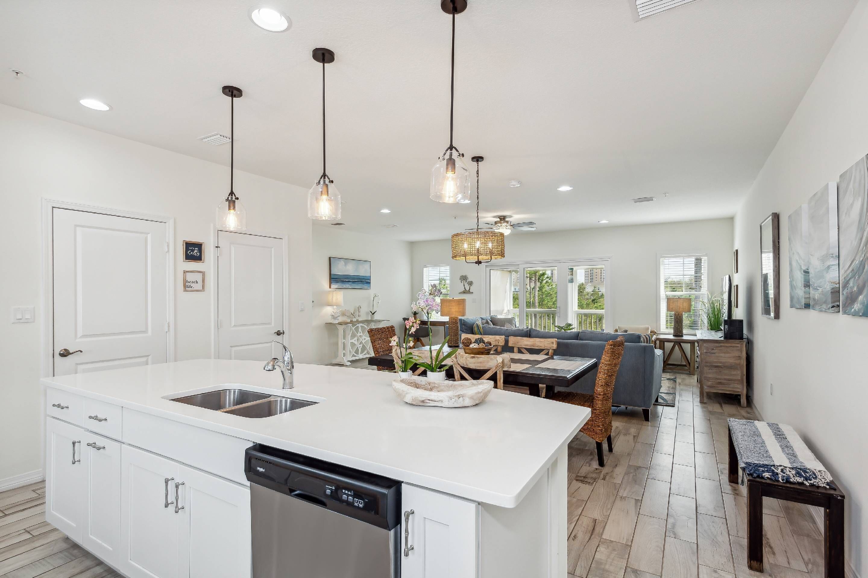 A modern kitchen with white cabinetry, a dishwasher, and pendant lights.