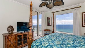 Un dormitorio con una cama grande, televisión, un armario de madera y vista al océano.