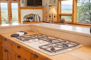 Una cocina con estufa a gas, armarios de madera, una encimera y vistas al exterior.
