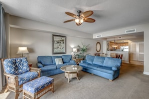 A living room with a ceiling fan, a dining area, and a kitchen.
