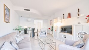 A modern living room with a sofa, armchair, glass coffee table, TV, and decorative items. - Beautiful Penthouse Near the Beach with Sea View, Pool, Wi-Fi, Air Conditioning, Balcony & Terrace (Torrox Costa)