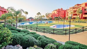 A resort with multiple swimming pools, palm trees, and red buildings. - Beautiful Penthouse Near the Beach with Sea View, Pool, Wi-Fi, Air Conditioning, Balcony & Terrace (Torrox Costa)