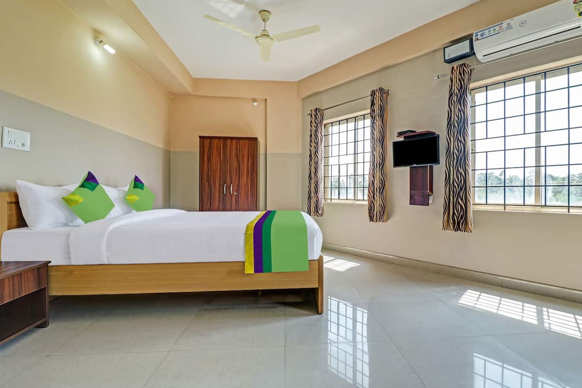 A hotel room with a bed, a wardrobe, a flat-screen TV, and a window with curtains.