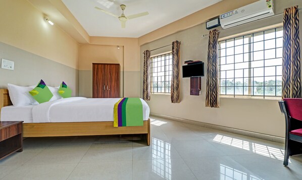 Una habitación de hotel con cama, armario, televisión de pantalla plana y ventana con cortinas.