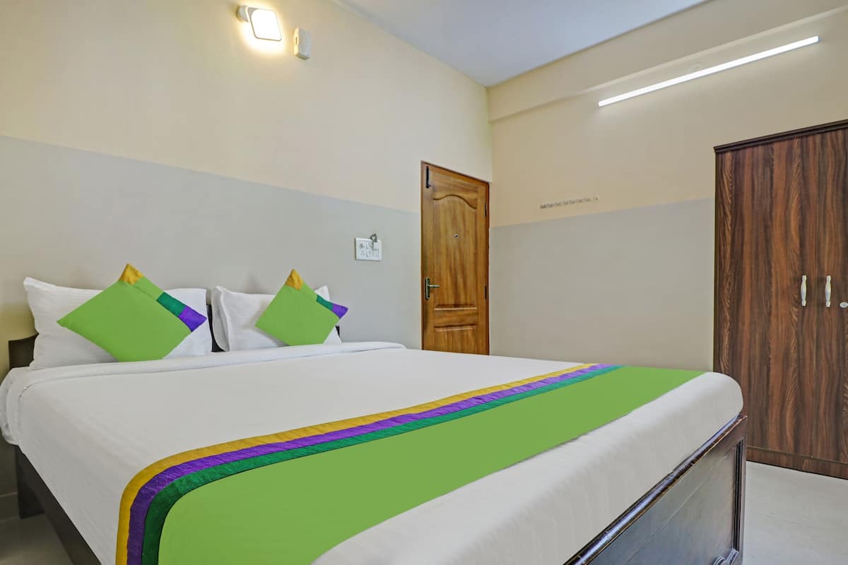 A hotel room with a bed, a wardrobe, and a wall-mounted light fixture.