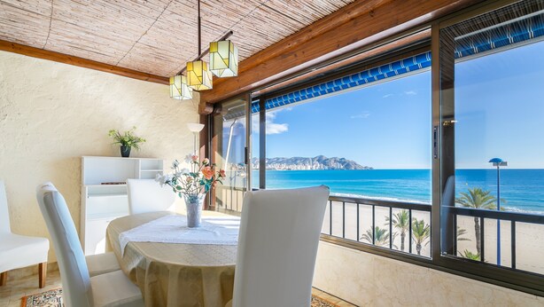 A dining area with a table, chairs, and a view of the ocean.