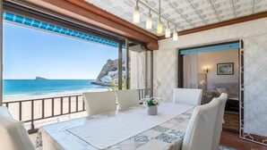 A dining area with a table set for two, a view of the sea, and a balcony with a railing.