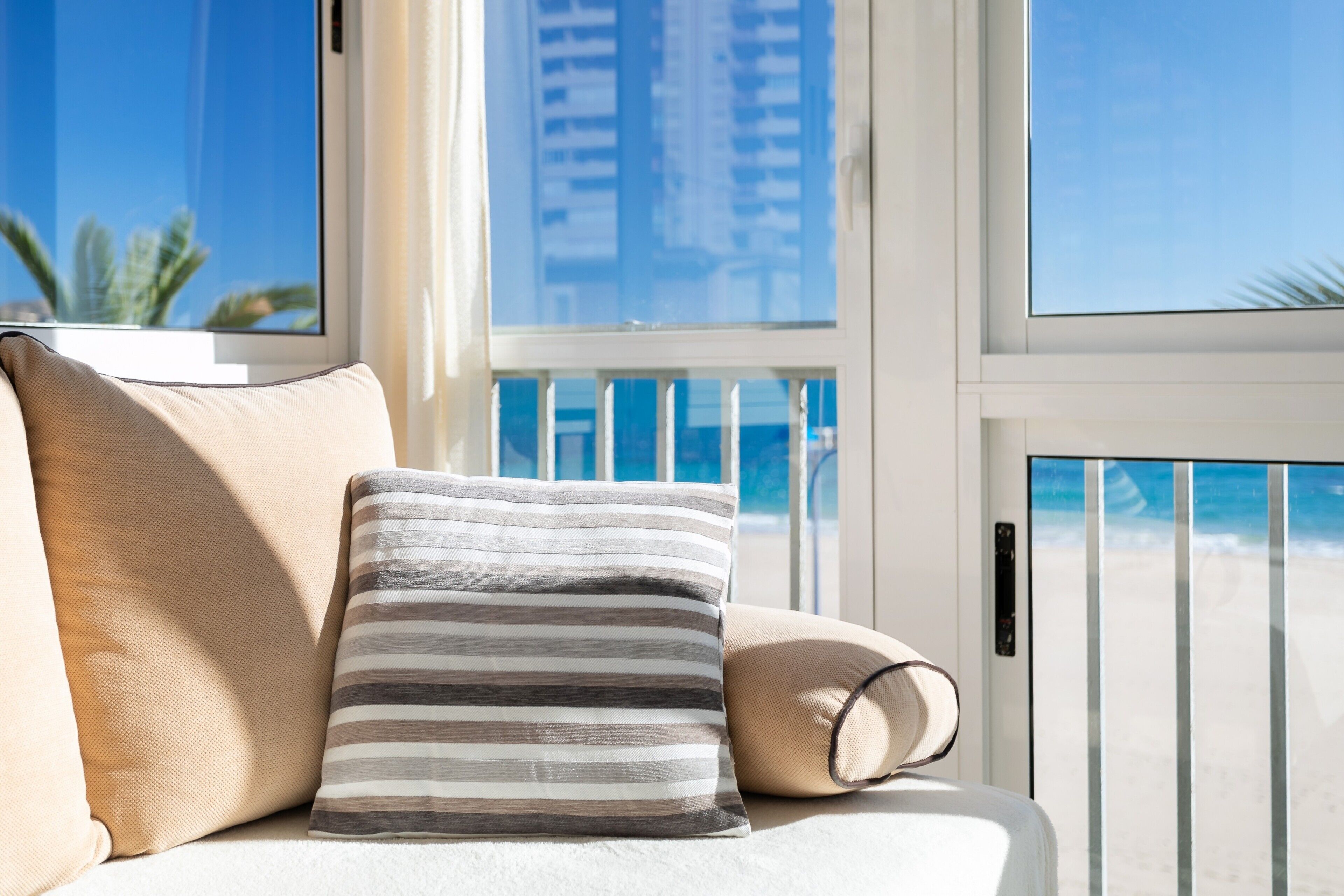 A balcony with a view of the beach and palm trees.