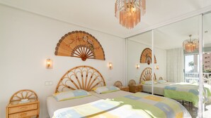 Une chambre avec deux lits, un grand miroir et un éventail décoratif.