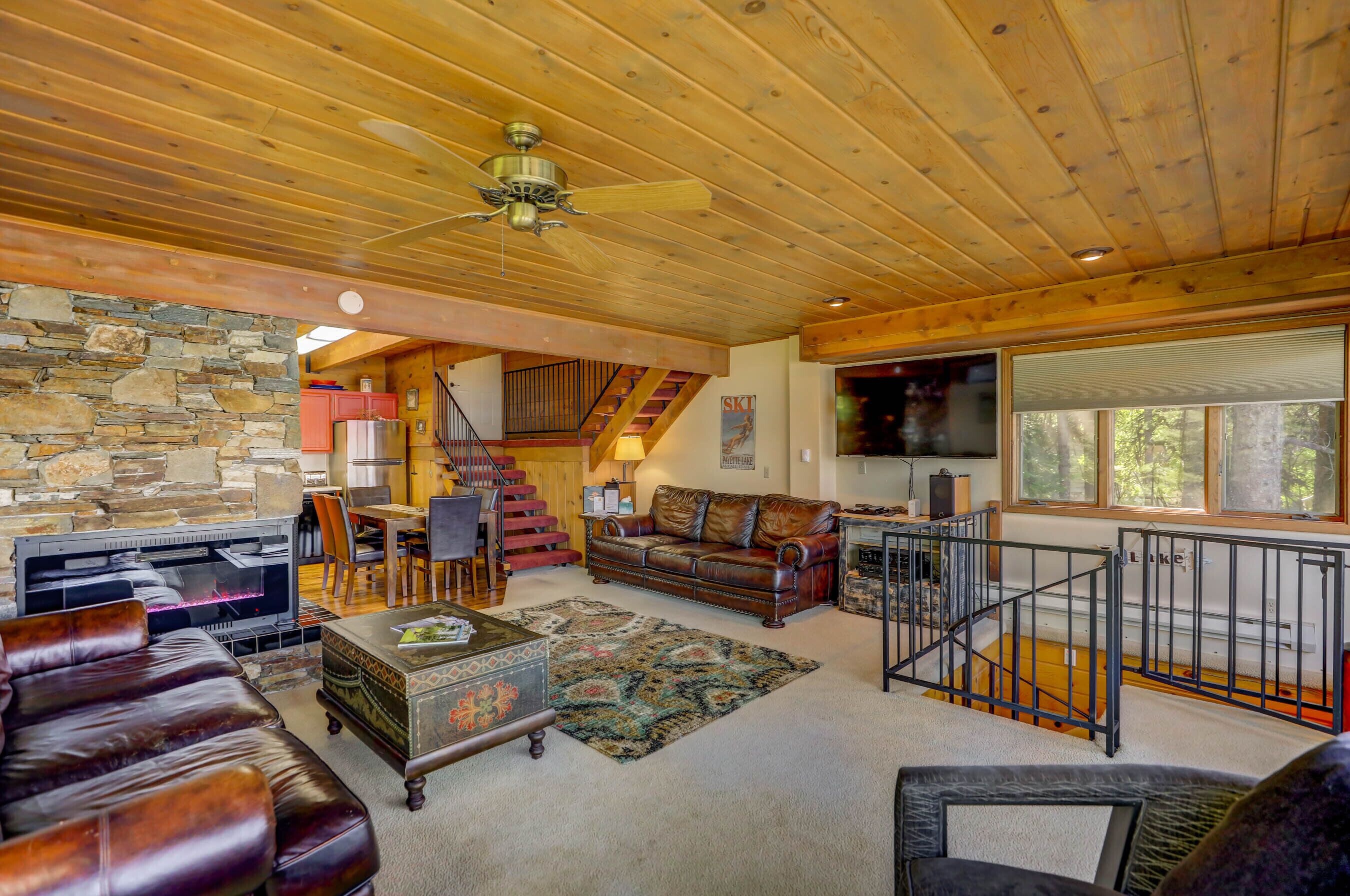 A cozy living room with a stone wall, leather furniture, a fireplace, and a TV.