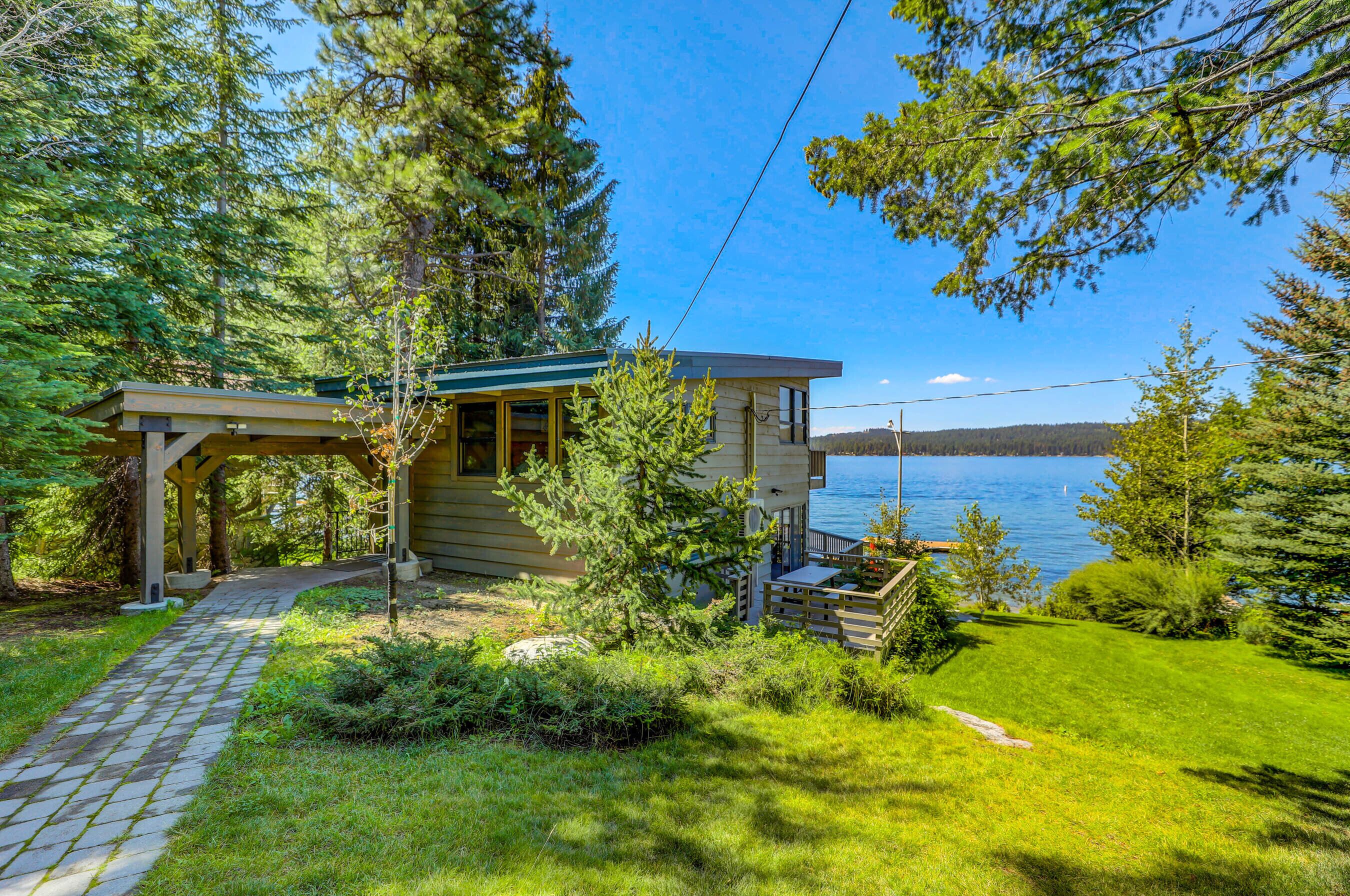 A cabin with a covered porch, a deck, and a view of a lake.