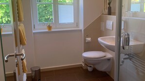 A bathroom with a toilet, sink, and a window with a potted plant. - Doppelzimmer 1 - Loensches Gut (Görlitz)