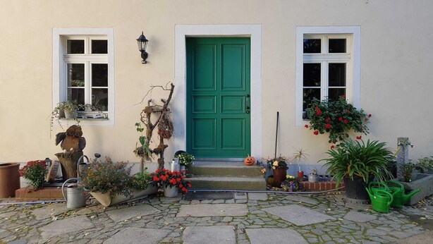 A house with a green door, two windows, and a stone-paved entrance. - Doppelzimmer 1 - Loensches Gut (Görlitz)