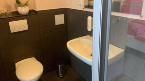 Une salle de bain moderne équipée de toilettes, d’un lavabo et d’un espace douche.