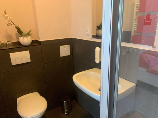 A modern bathroom with a toilet, sink, and shower area.