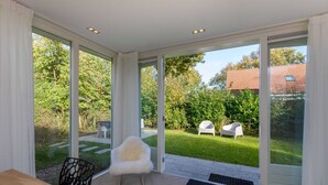 Ein modernes Zimmer mit großen Schiebeglasfenstern, die zu einem Garten führen.