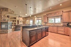 A spacious kitchen with a large island, wooden cabinets, and a stone accent wall. - Game Room & Community Amenities: Overgaard Home! (Overgaard)
