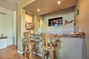 A bar area with wooden chairs and a TV mounted on the wall.