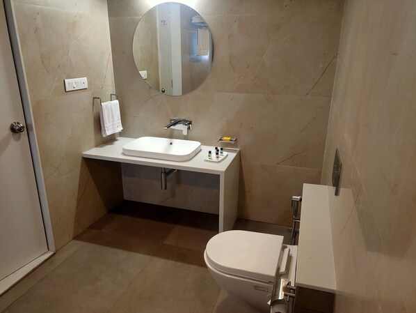 A bathroom with a white sink, mirror, and toilet. - The Somnath Gateway (Veraval)