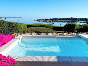 Une piscine à l’eau d’un bleu cristallin, entourée de verdure et de rochers.