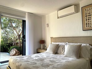 Une chambre à coucher avec un lit, une table de chevet, une lampe et une fenêtre avec des rideaux.