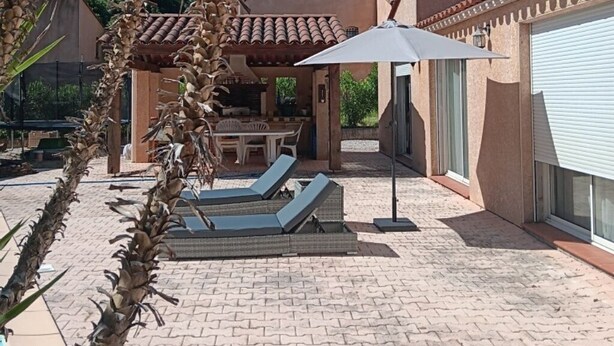 A patio area with a table and chairs, a covered seating area, and a large umbrella.