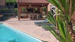 A swimming pool with a barbecue area and lounge chairs.