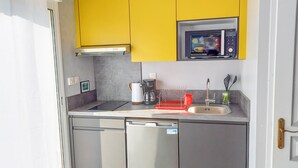 A compact kitchen with yellow cabinets, a microwave, a coffee maker, and a dishwasher.