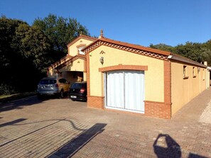 Um edifício com telhado de cerâmica, porta de garagem e calçada pavimentada.