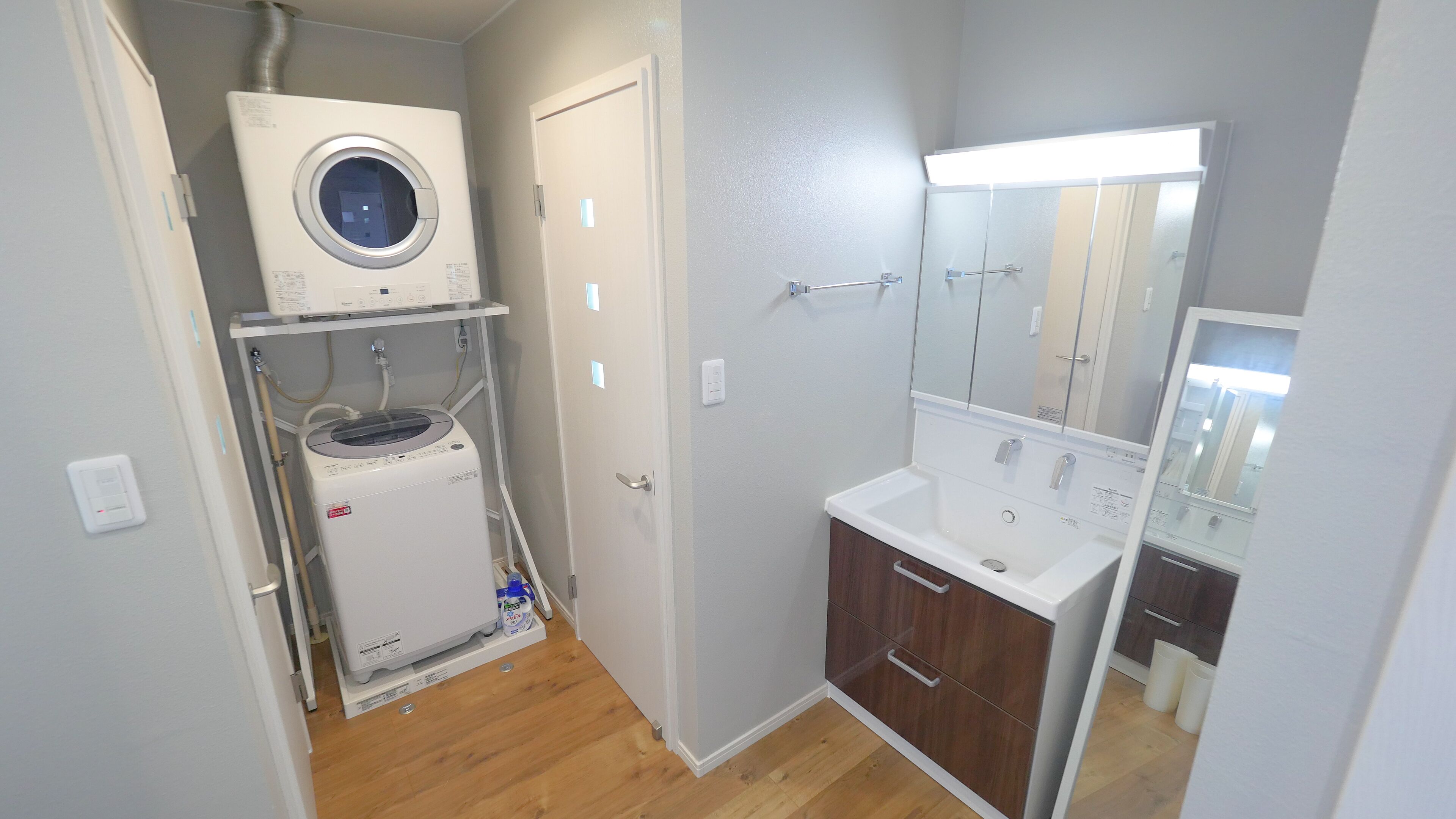 Un baño pequeño con lavadora integrada, un lavamanos y un espejo.