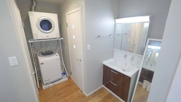 Un baño pequeño con lavadora integrada, un lavamanos y un espejo.