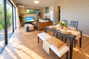 Uma sala de estar moderna com área de jantar, janelas amplas e vista para o exterior.