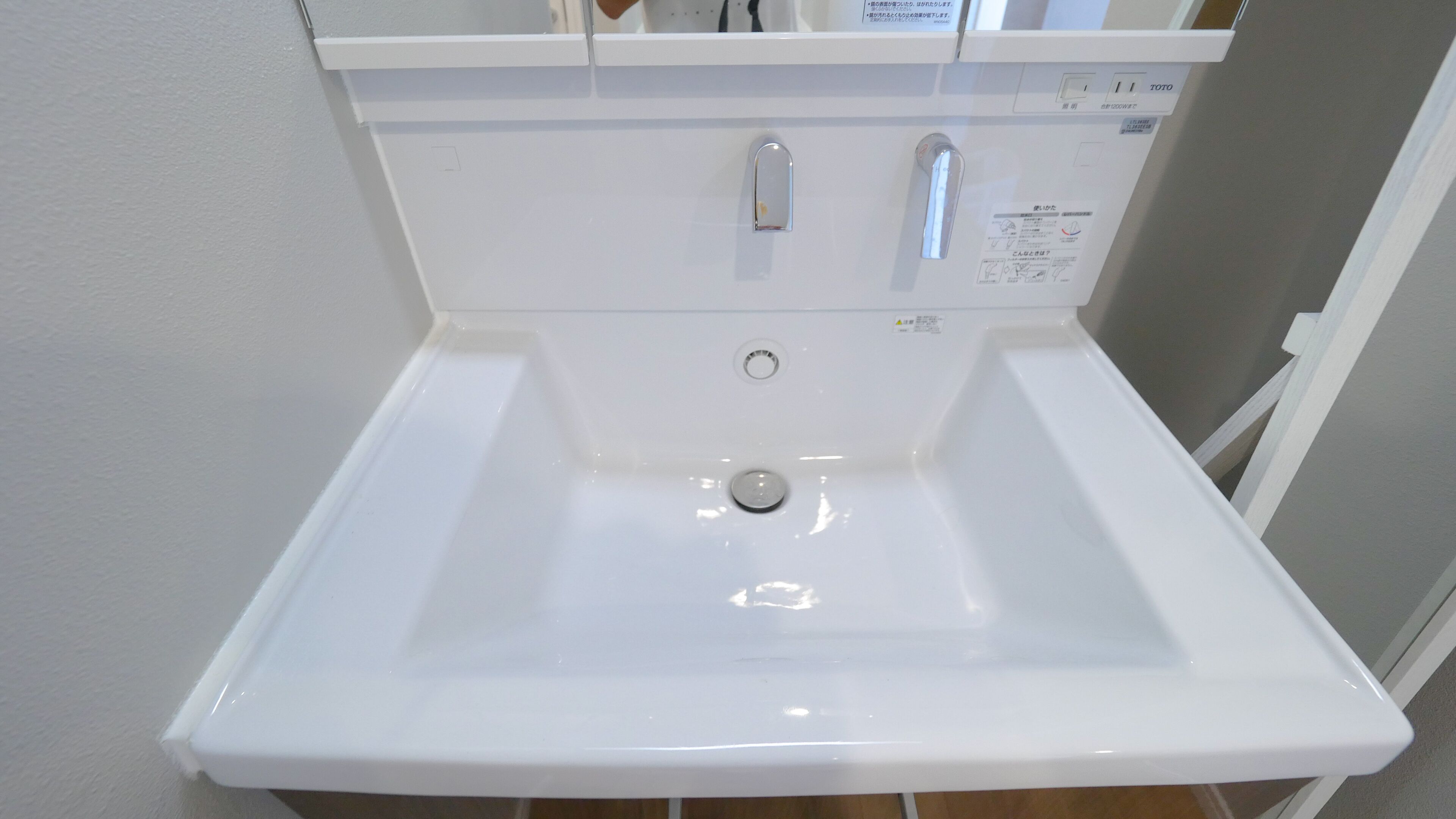 Een witte wastafel met een spiegel erboven en een kraan aan de rechterkant.