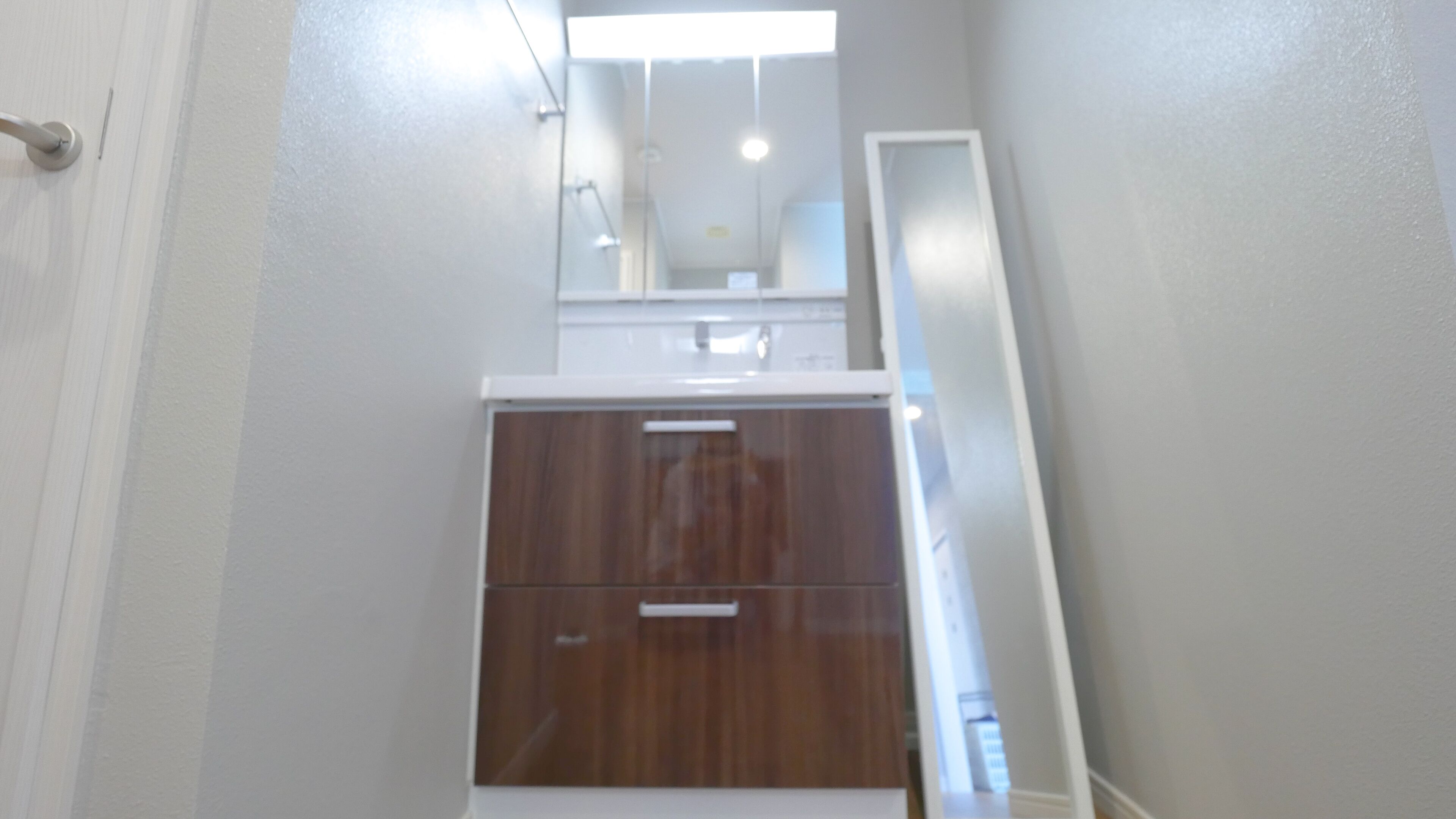 A narrow hallway with a wooden cabinet and a white door.