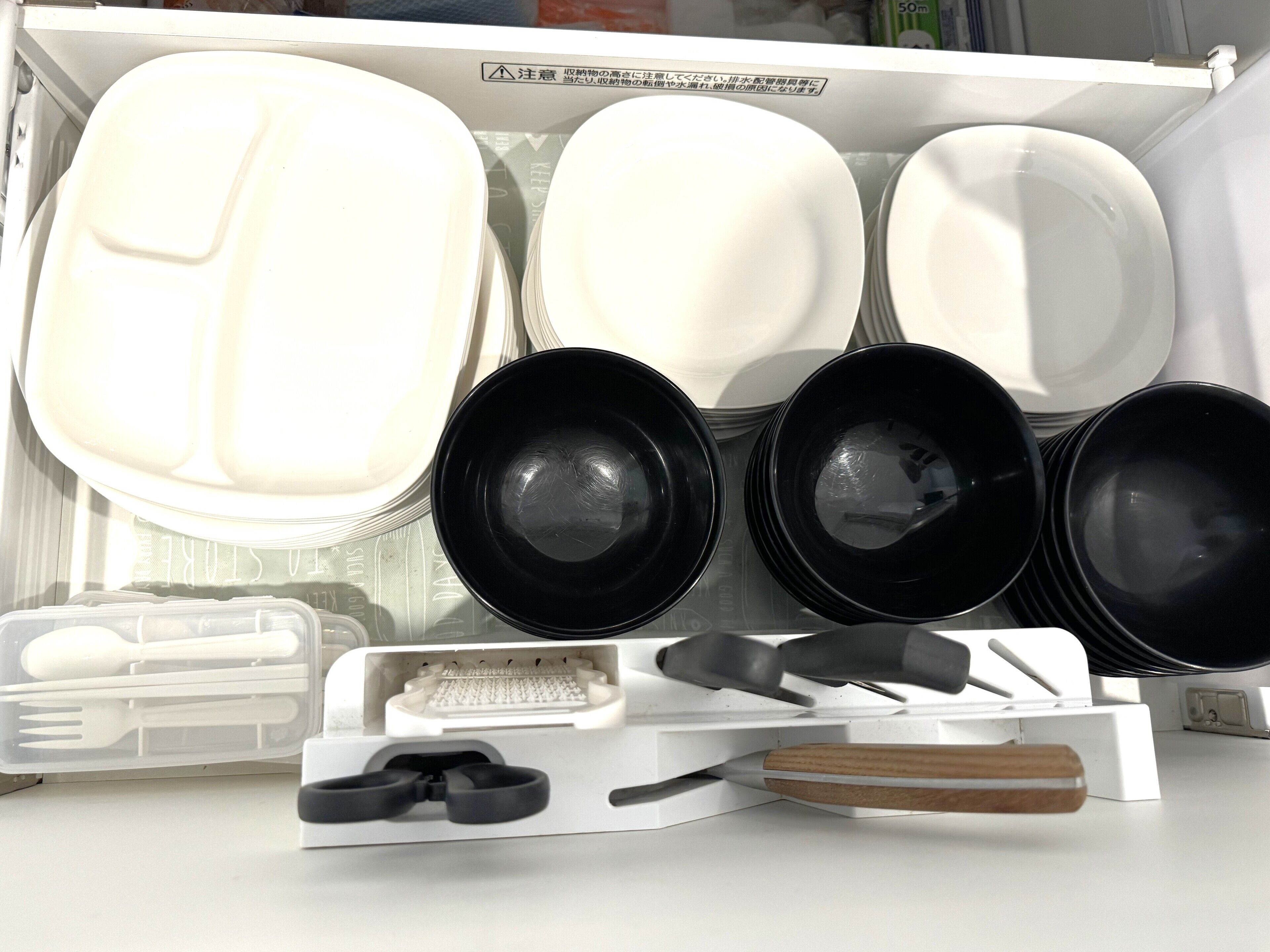 A kitchen with white cabinets, black cookware, and a wooden-handled utensil.