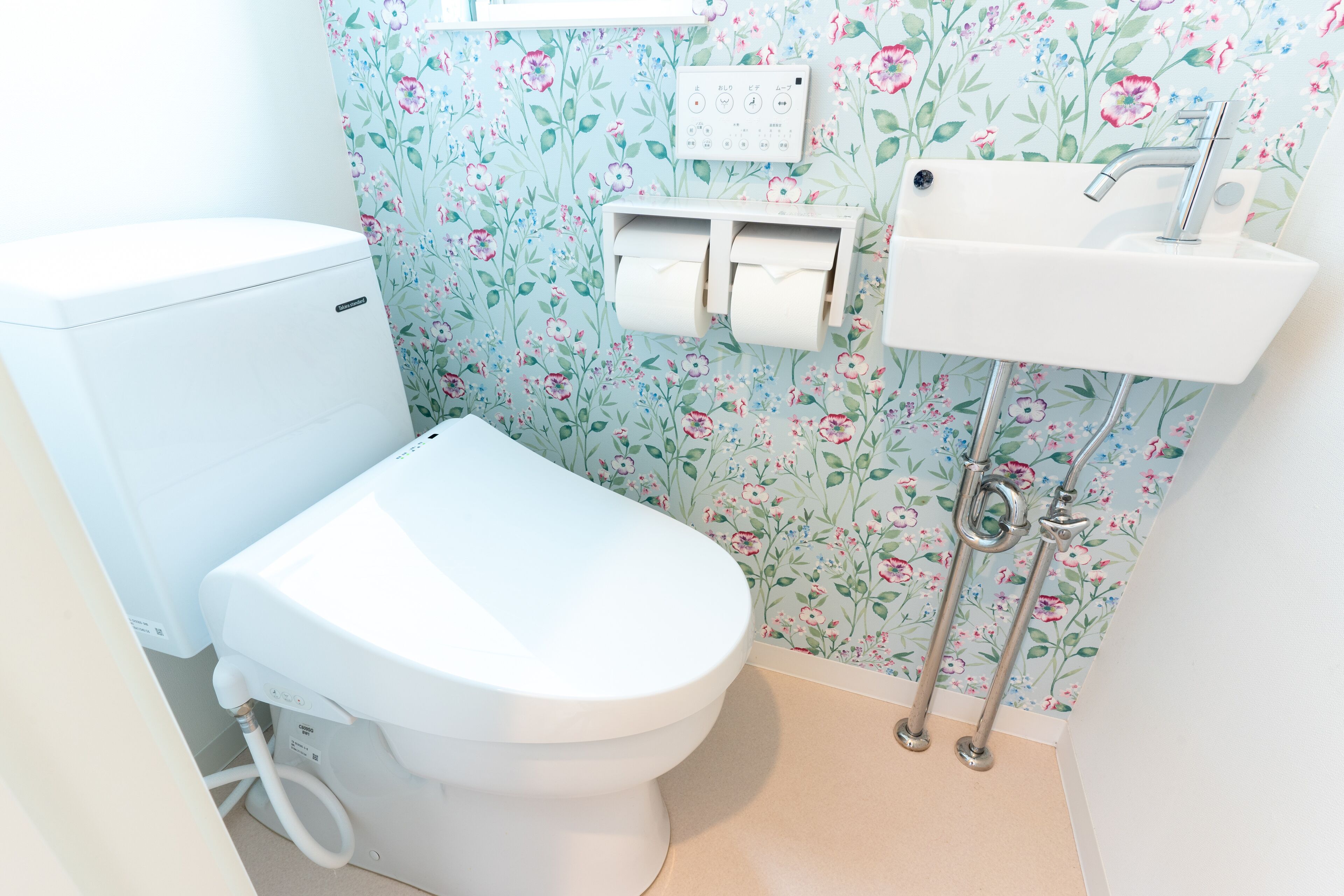 Un baño con inodoro, lavamanos y dispensador de papel higiénico.