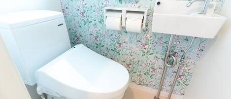 Un baño con inodoro, lavamanos y dispensador de papel higiénico.