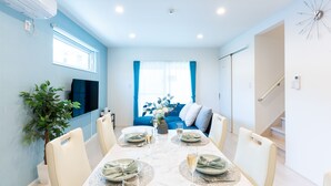 A dining area with a table set for four, a television on the wall, and a staircase leading to another level.