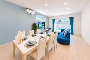 Un comedor moderno con una mesa dispuesta para cuatro personas, un sofá azul y un ventanal con cortinas.