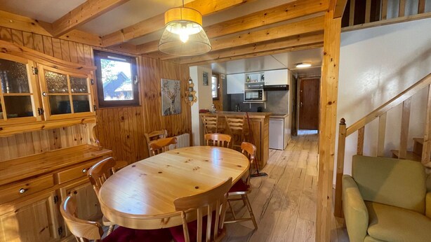 Un interior de madera con una mesa de comedor, sillas, una zona de cocina y una escalera.