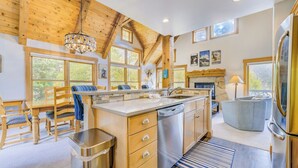 A modern kitchen with wooden beams, a large island, and a view of the outdoors.