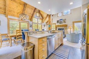 A modern kitchen with wooden beams, a large island, and a view of the outdoors. - Cabins in the Pines #2 by Summit County Mountain Retreats (Keystone)