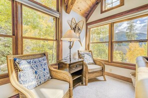 A cozy room with large windows, wicker furniture, and a lamp.