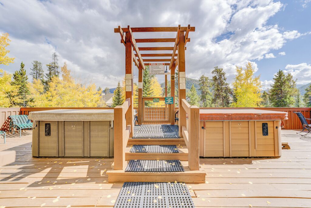 A pool area with wooden steps leading to a pool, surrounded by covered storage units and a wooden deck.