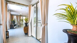 Zona d'estar àmplia amb una porta corredissa de vidre que dona a un balcó, zona de menjador i televisió al fons.