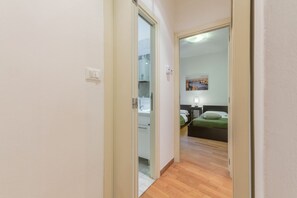 A hallway leading to a bedroom with a bed, a nightstand, and a painting on the wall. - GuestHost - Bologna Giardini Margherita Apartment (Bologna)