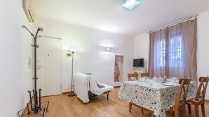 Un comedor con una mesa dispuesta para cuatro personas, una silla, una lámpara de pie y un perchero.