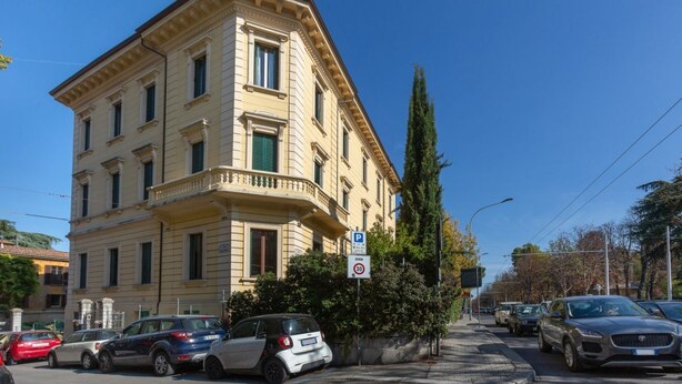 Un edificio de varios pisos con estilo arquitectónico clásico, que cuenta con un balcón en la planta baja.